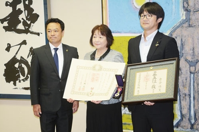 写真：特旨叙位と特別叙勲の伝達を受けた早苗さん（中央）と佑介さん（右）