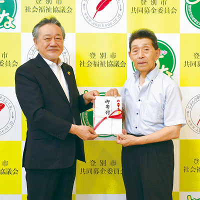 写真：仲川会長に善意を手渡す斉藤会長（右）