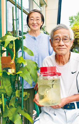 写真：焼酎漬けにした月下美人を手にする吉村夫妻
