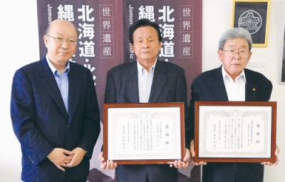 写真：感謝状を手にする伊藤社長（右）と田村社長。左は堀籠教育長