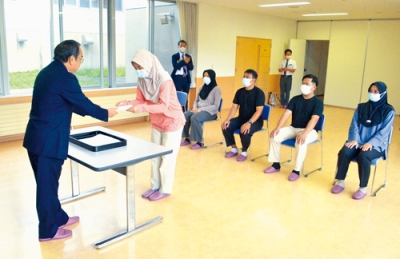 写真：大柴茂理事長（左）から辞令を受け取るインドネシア出身の介護職員