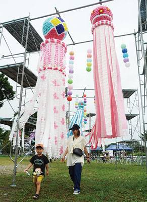 写真：七夕飾りの下をくぐる子ども連れ
