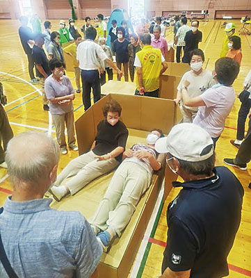 写真：段ボールベッドを組み立て座り心地などを確認する参加者