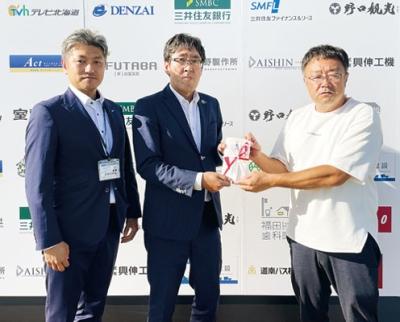 写真：上村理事長（右）へ寄付金を手渡す本社・山田営業局長（中央）と長内中部支社長