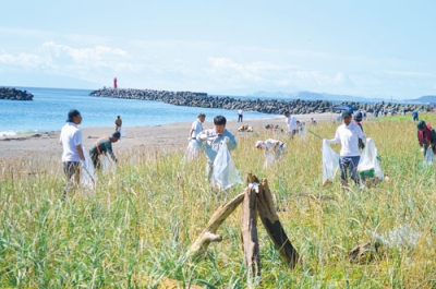 写真：漁港周辺の砂浜に流れ着いたごみを拾い集める参加者たち