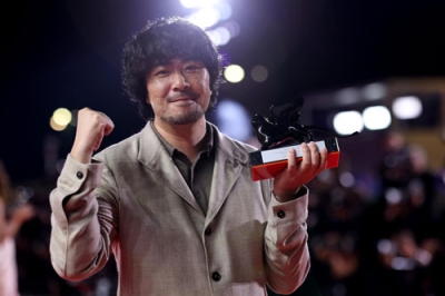 写真：ベネチア国際映画祭でオリゾンティ部門の審査員特別賞を受賞し、トロフィーを持つ藤元明緒監督＝６日、イタリア・ベネチア（ゲッティ＝共同）
