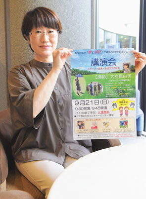 写真：講演会のポスターを手にする大岩さん