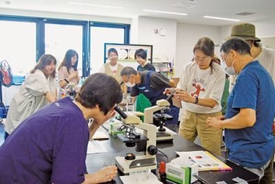 写真：顕微鏡で納豆菌などの微生物を観察する参加者ら