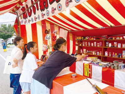 写真：露店の射的を楽しむ祭り客