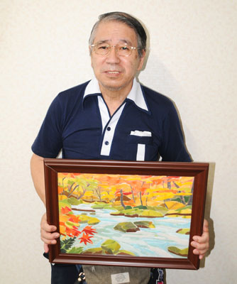 写真：作品を手に来場を呼びかける中村さん