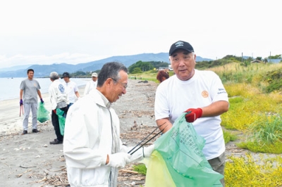 写真：砂浜に落ちたごみを火ばさみで拾う伊達ＲＣの会員たち