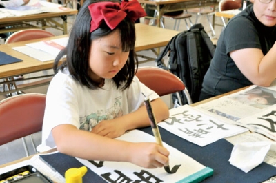 写真：真剣な表情で書に臨む児童