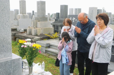 写真：墓前で手を合わせる家族連れ＝２０日午前１０時半ごろ、室蘭市神代町