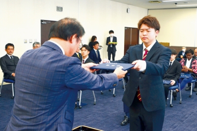 写真：松田学長（左）から学位記を受け取る学生