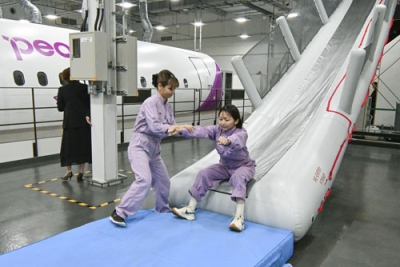 写真：ピーチの複合研修施設で、緊急脱出スライドを使って訓練する社員＝７月、関西空港