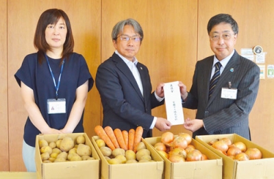 写真：髙木康事務局長に善意を手渡す吉川営業部長（中央）と佐藤由香さん