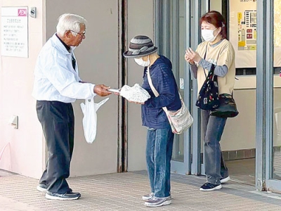 写真：買い物客に啓発物を配る参加者