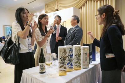 写真：ベトナムの首都ハノイで、日本酒の説明を受ける地元観光会社の社員ら＝９月３０日（共同）