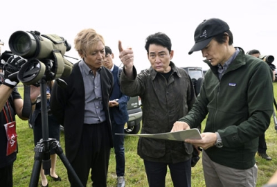 写真：説明を聞きながら釧路湿原周辺にある大規模太陽光発電所の建設予定地を視察するアルピニストの野口健さん（中央）＝２日午前、釧路市