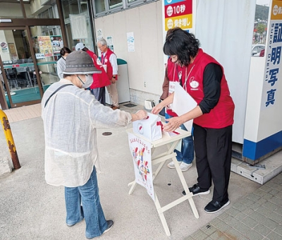 写真：赤い羽根の街頭募金に協力する市民（左）