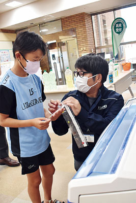 写真：分包機で袋に分けて包まれた菓子を受け取る子ども