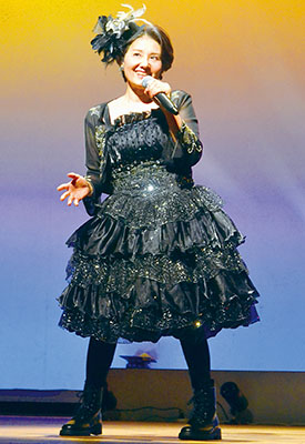 写真：きらびやかな衣装で踊りながら熱唱する出演者