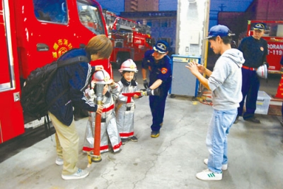 写真：防火服を着て消防士気分を味わう子どもたち