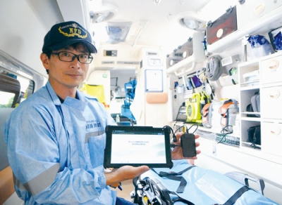 写真：マイナ保険証を読み込むタブレットを手にする伊達消防署の救急隊員