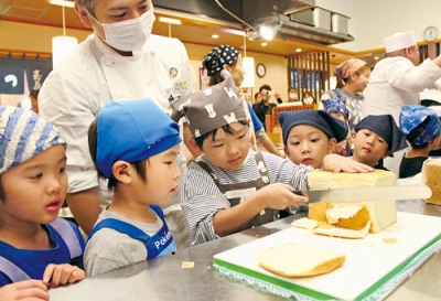 写真：「ゆっくりね」。慎重にパンの耳を切る園児ら