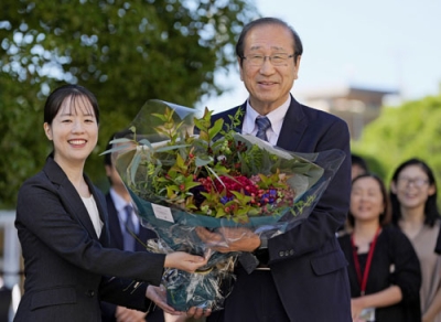 写真：ノーベル化学賞の受賞決定から一夜明け、職員から花束を受け取る京都大の北川進氏（右）＝９日午前、京都市左京区