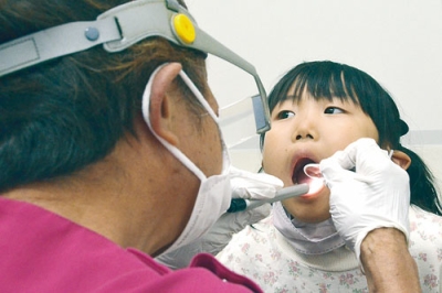 写真：大きく口を開けて歯科健診を受ける幼児