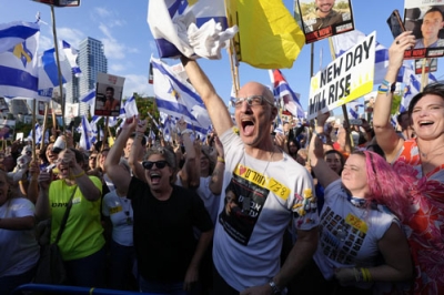 写真：人質の引き渡しが始まったと報じられ、喜ぶ人たち＝１３日、イスラエル中部テルアビブ（共同）