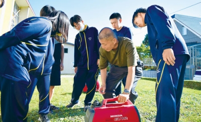 写真：町の防災担当者から発電機の使い方を学ぶ生徒たち（提供写真）