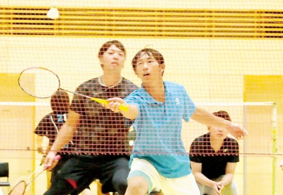 写真：腕を伸ばしてシャトルに食らいつく男子選手
