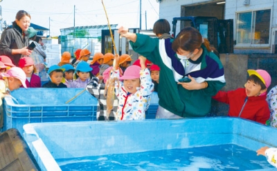 写真：イカを釣り上げ、笑顔を見せる海の子保育園の園児