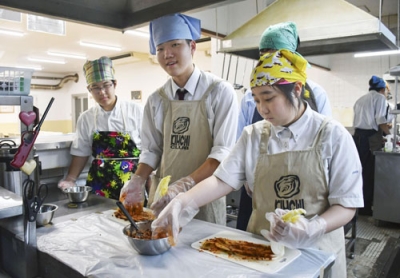 写真:白菜にタレを塗り込む部長の鳥取泰介さん(中央)ら大阪偕星学園高キムチ部員=9月、大阪市生野区