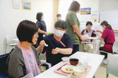 写真：食事介助の実習に臨む研修参加者ら