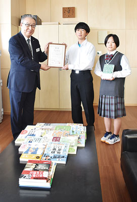 写真：壮瞥中代表生徒へ真新しい図書を贈る川上参事（左）