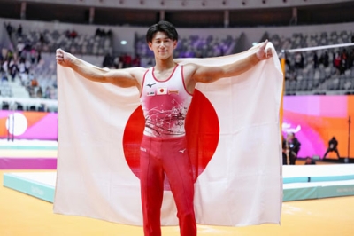 写真：体操の世界選手権男子個人総合で３連覇を果たし、日の丸を掲げる橋本大輝＝２２日、ジャカルタ（共同）