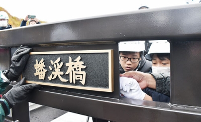 写真：「蟠渓橋」の橋名板を取り付ける壮瞥小の６年生