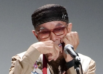 写真：口琴の国際大会の開会式で演奏する奏者＝２４日午前、釧路市の阿寒湖アイヌコタン