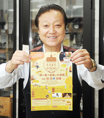 写真:ポスターを手にイベントをPRする酒本代表