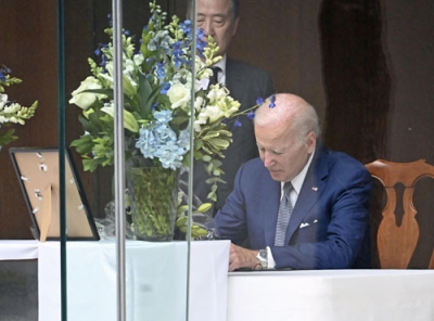 写真:2022年7月、安倍元首相の死去を受け、米ワシントンの日本大使公邸で記帳するバイデン大統領(共同)