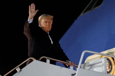 写真:24日、米大統領専用機に乗り込む前に手を上げるトランプ大統領=ワシントン郊外(ロイター=共同)