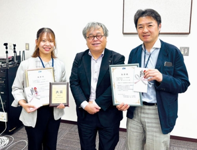 写真：受賞を喜ぶ、室蘭まちづくり放送の森さんと星康洋さん（右）。中央は杉澤会長