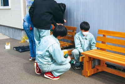 写真:手作りのベンチを設置する室蘭工業高の生徒