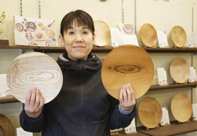 写真：里山の木で作られた皿を手に持つ木工クラフト工房「チエモク」の三島千枝社長＝札幌市