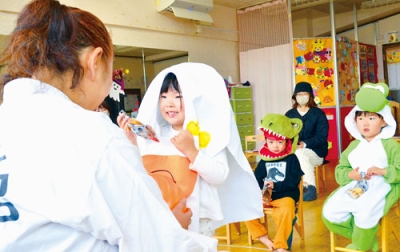 写真:「トリック・オア・トリート」と元気に声をかけ、菓子をもらう園児たち