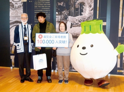 写真:来場10万人目となった竹内さん(左から2人目)