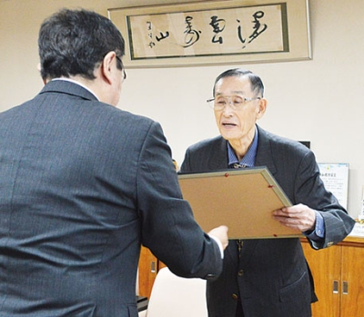 写真:小笠原市長から勲記と勲章を受け取る橋詰さん